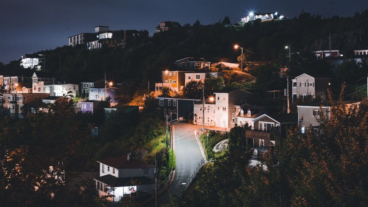 Illuminated hillside residential neighborhood with street lights glowing at night, showcasing serene landscapes.