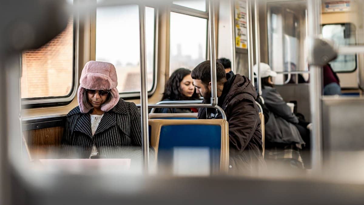 Passengers wearing winter coats and hats on a train during a city commute.