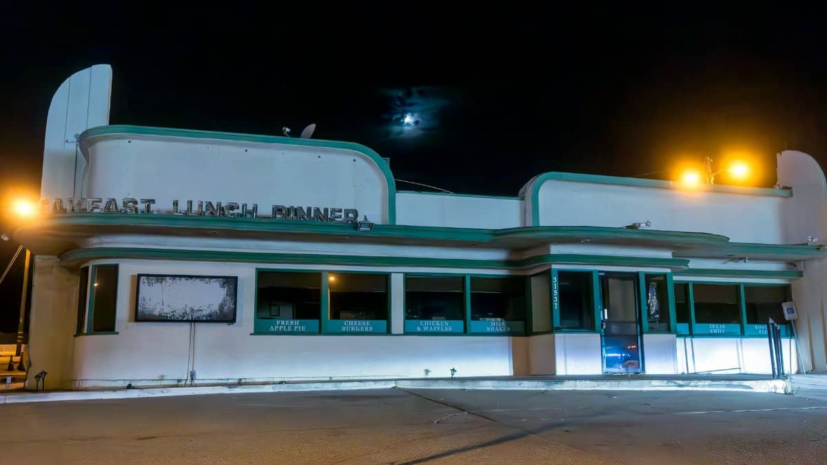 Vintage diner facade lit by streetlights and moonlight at night, exuding nostalgic charm.