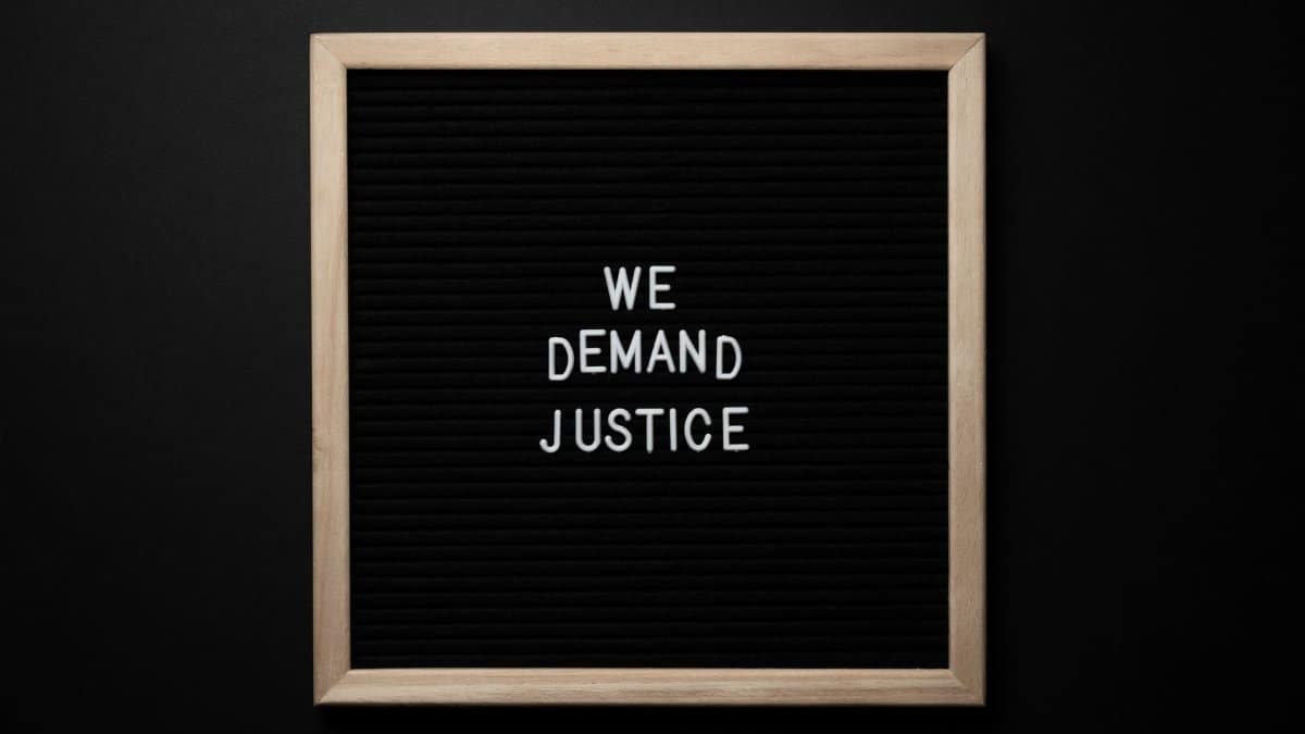 From above wooden frame with we demand justice text placed on black table
