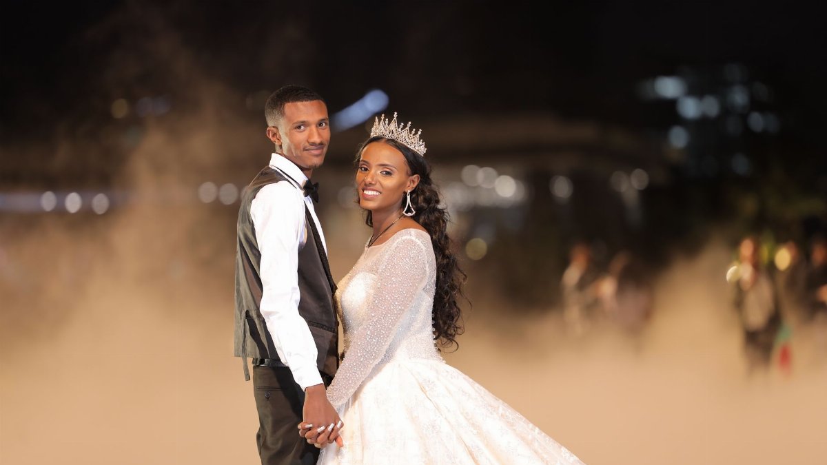 A beautiful couple in wedding attire holding hands at an enchanting night ceremony.