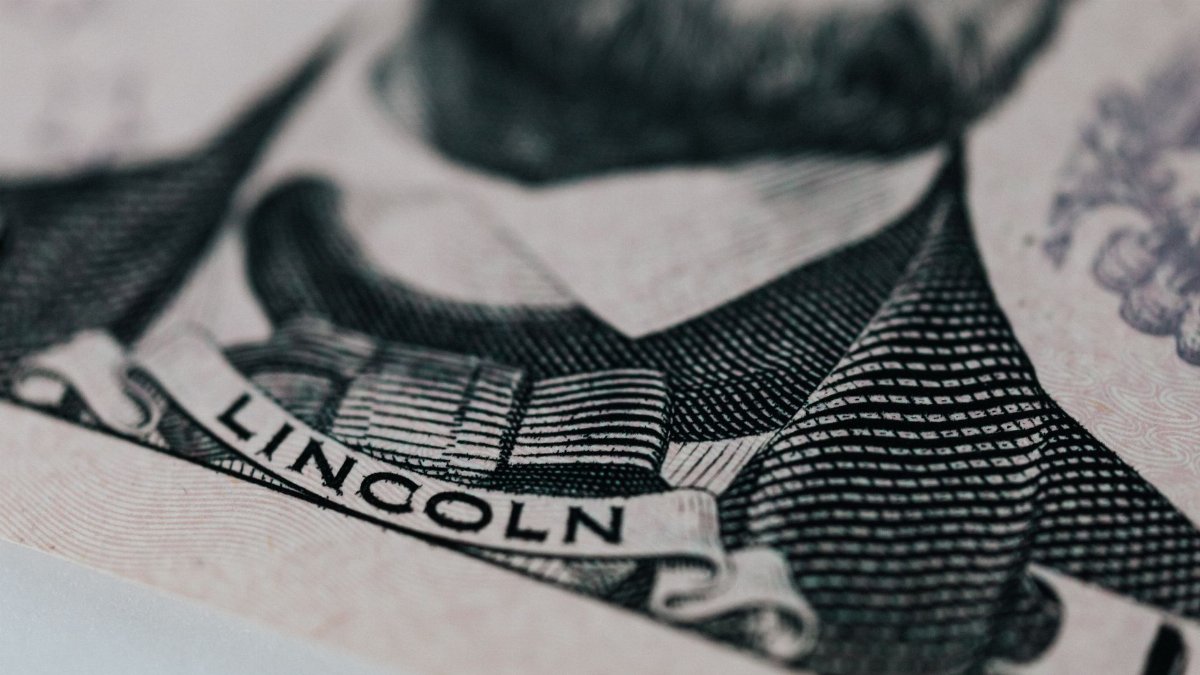 Crop of five dollar banknote with president Lincoln wearing costume on table