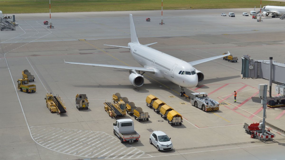 High angle view of a commercial airplane on airport tarmac with ground support vehicles.