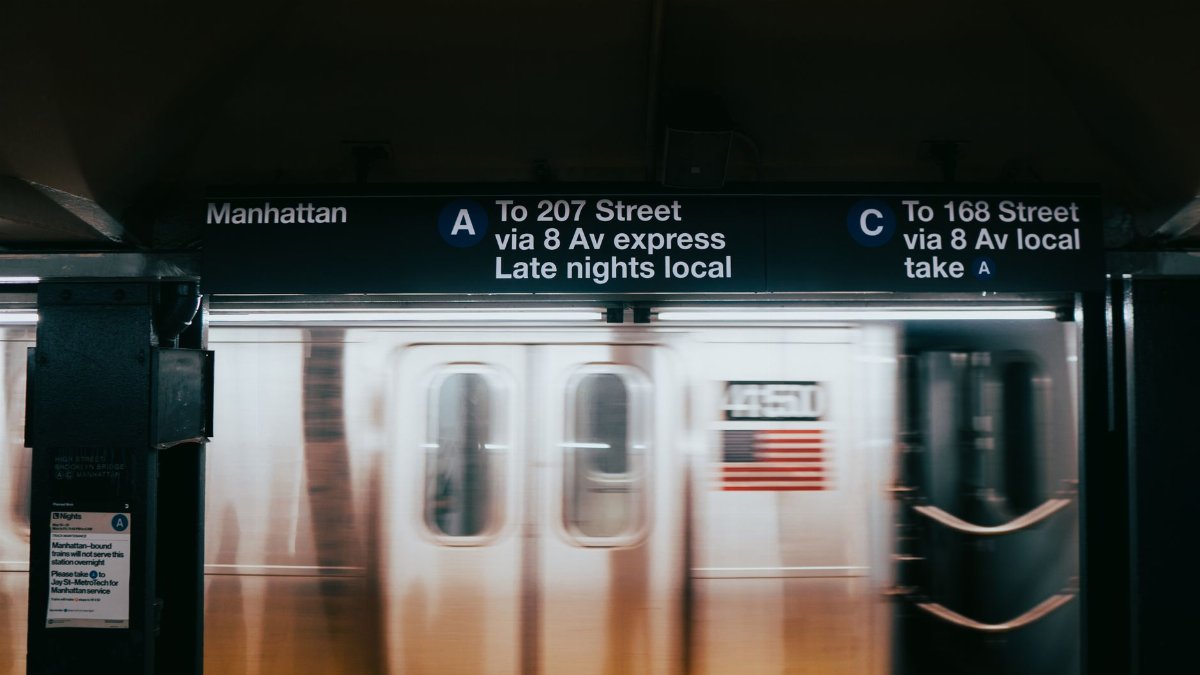 A blurred image of a subway train passing through Manhattan's station in New York City at night.