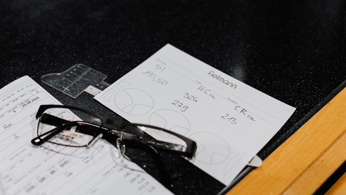 Eyeglasses resting on various forms on a black surface, symbolizing vision and assessment.