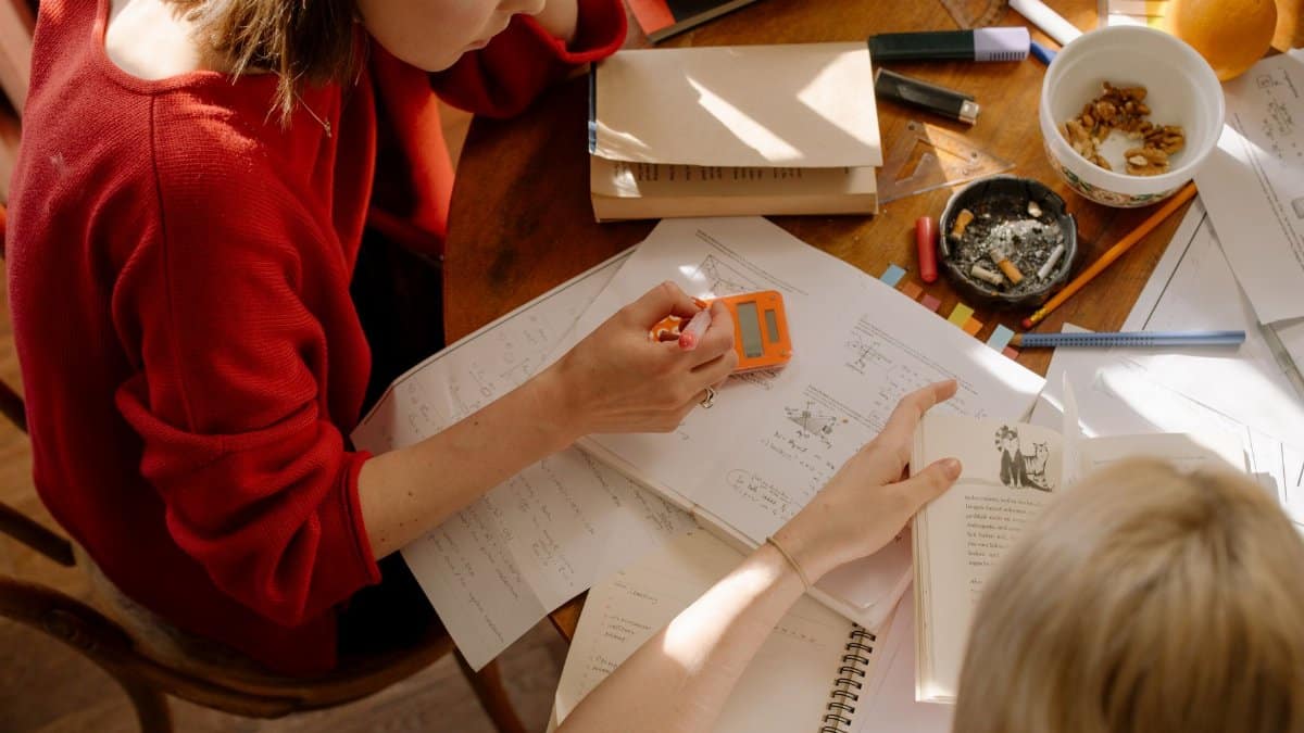 Two students engaged in studying at a table with textbooks, notes, and stationery.