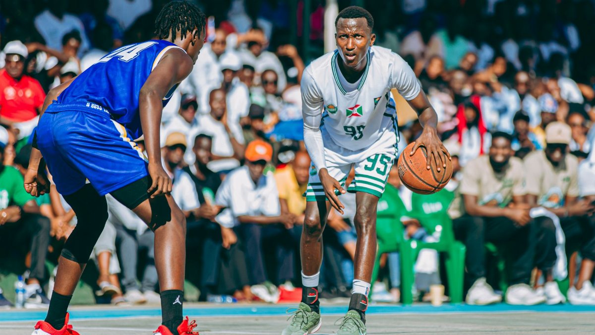 Intense outdoor basketball match with two players in focus, surrounded by a large audience.