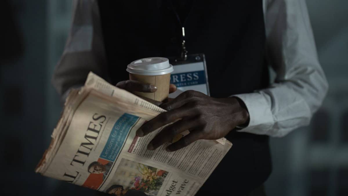 Close-up of a journalist holding a newspaper and coffee cup, conveying press and media concept.