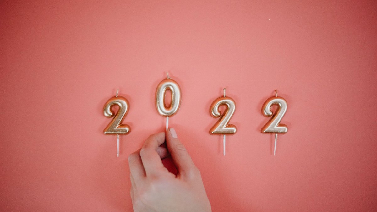 Celebrate the New Year 2022 with golden number candles on a pink backdrop.