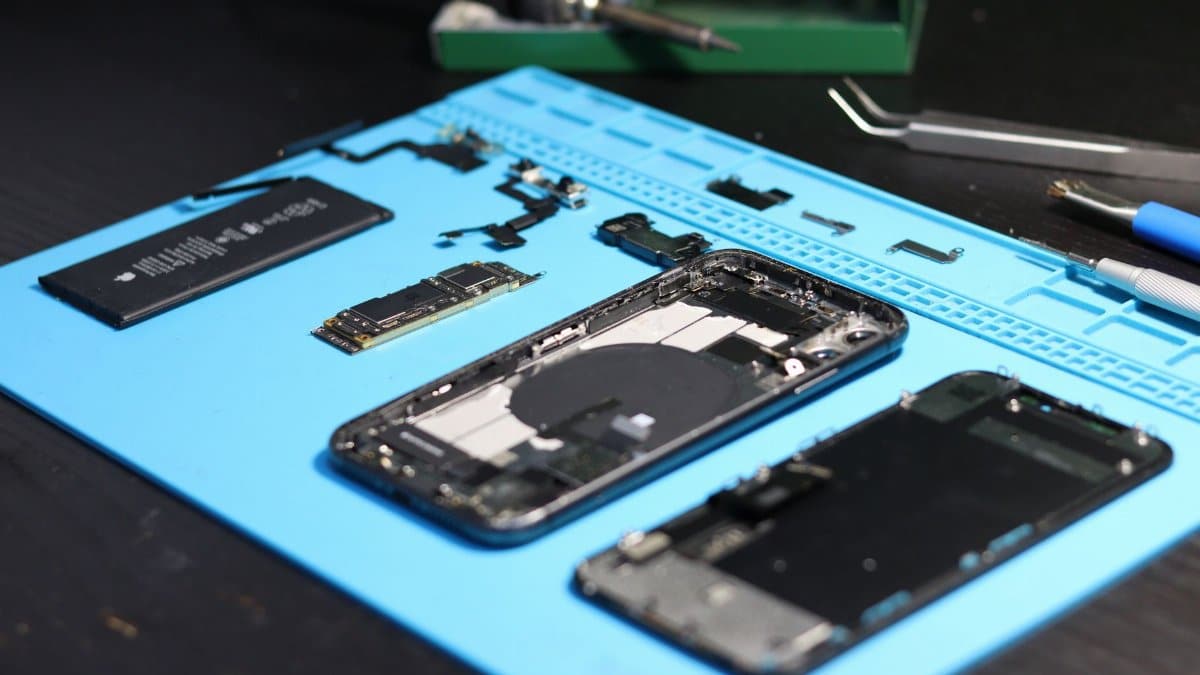 Disassembled smartphone with tools on a workbench, emphasizing repair and technology.