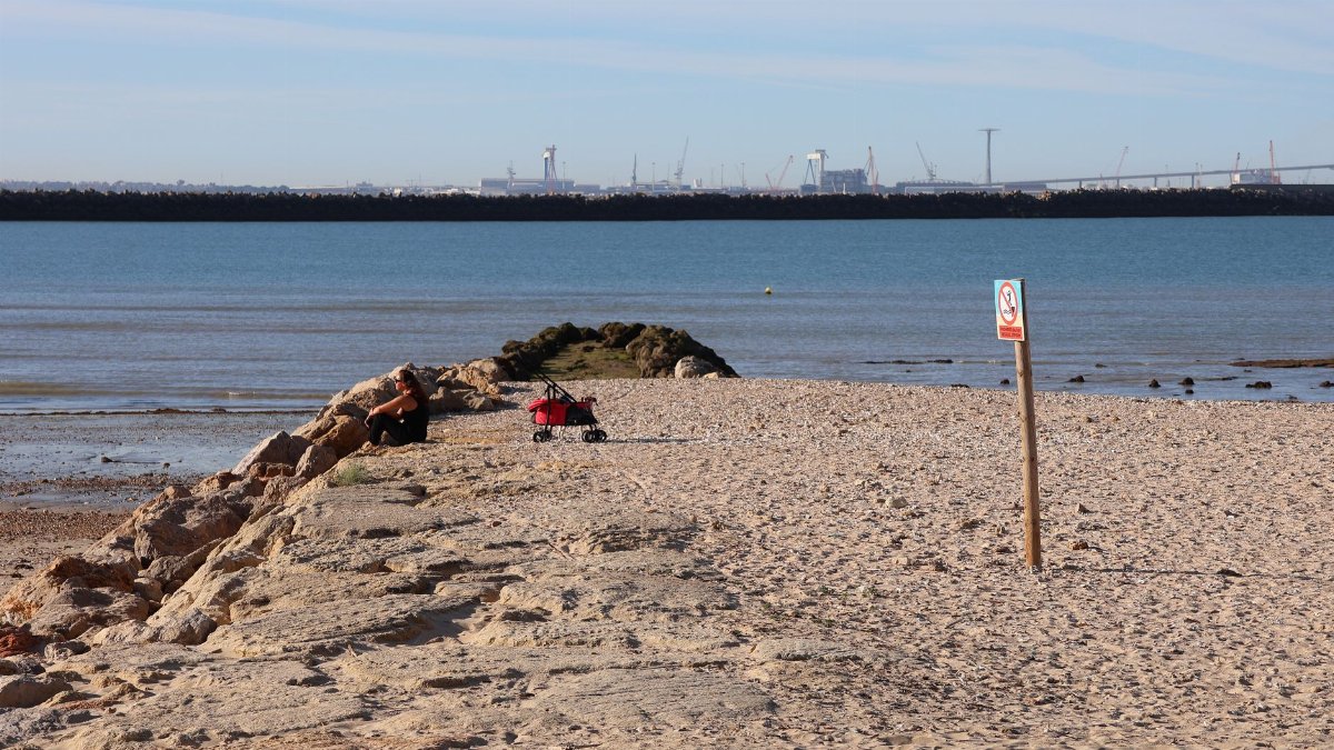 Sunny beach scene at El Puerto de Santa María, Andalucía, showcasing calm waters and distant cityscape.