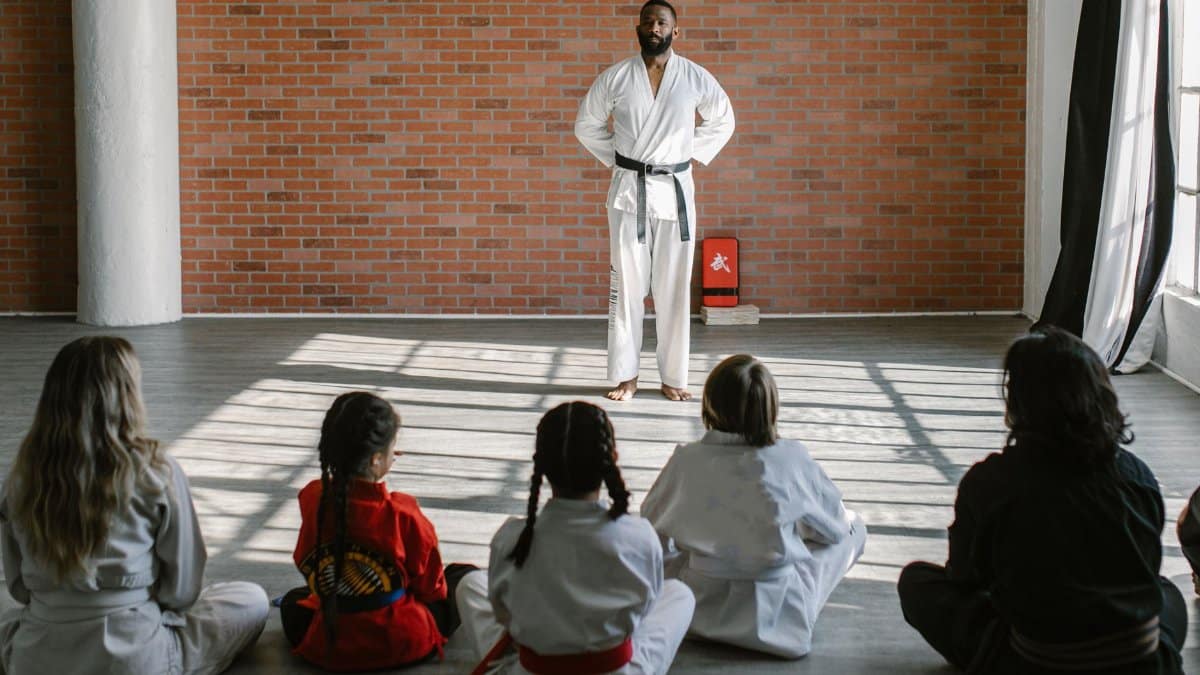 Young students in gis learn martial arts under the guidance of a black belt sensei in a dojo setting.