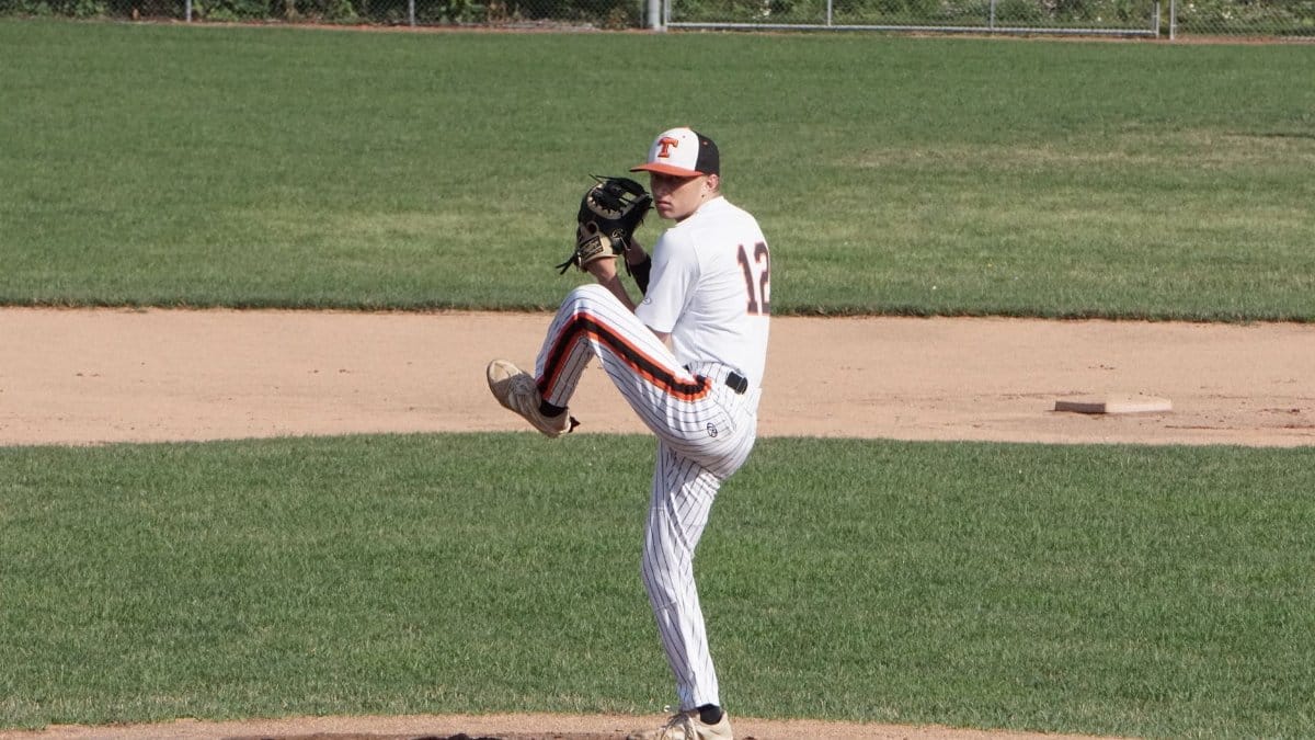 A focused baseball pitcher preparing to pitch during an outdoor game on a sunny day.