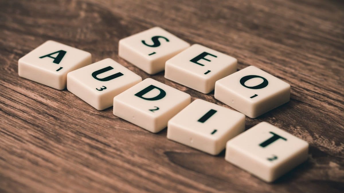 Scrabble tiles spelling SEO Audit on wooden surface, symbolizing digital marketing strategies.