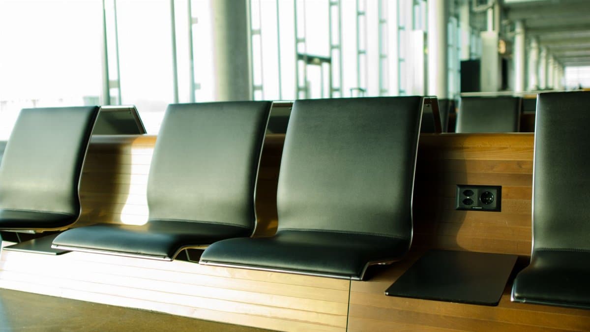 Empty airport seating area with sunlight streaming in, creating a tranquil atmosphere.