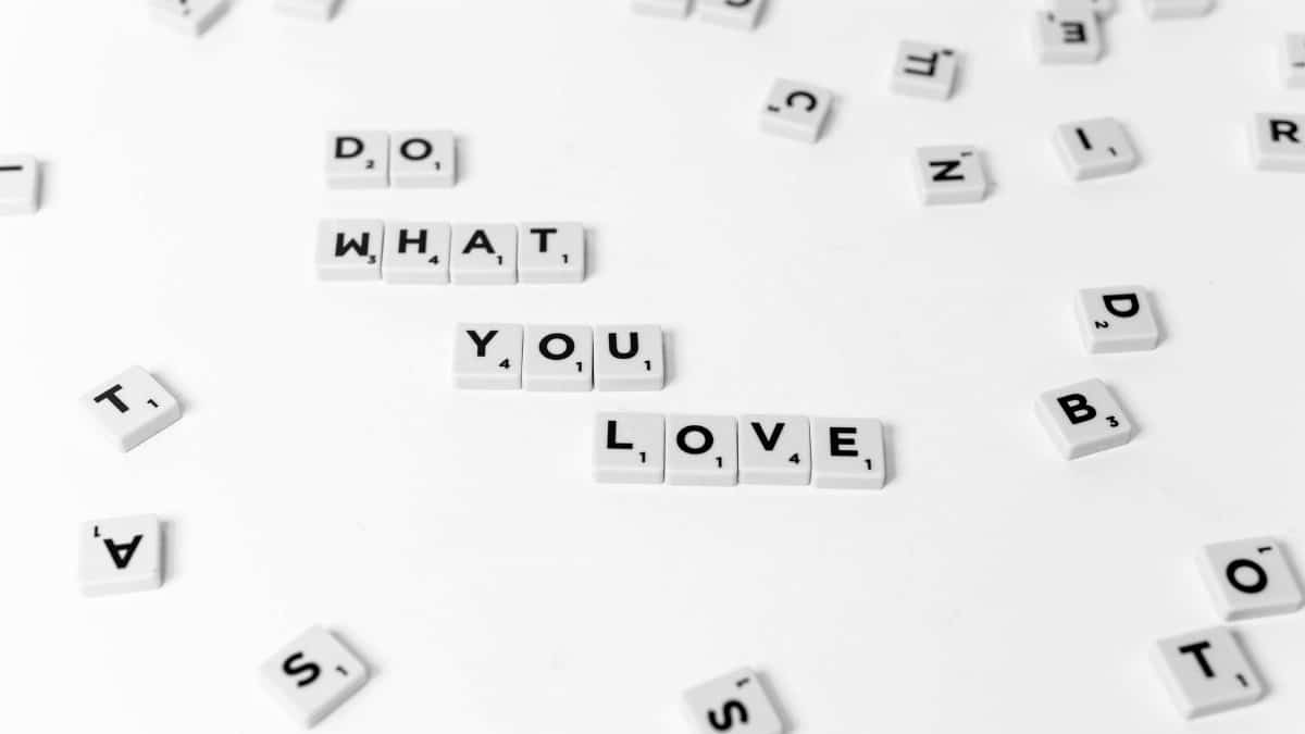 Minimalist photo of scrabble tiles spelling 'DO WHAT YOU LOVE' on a white background.
