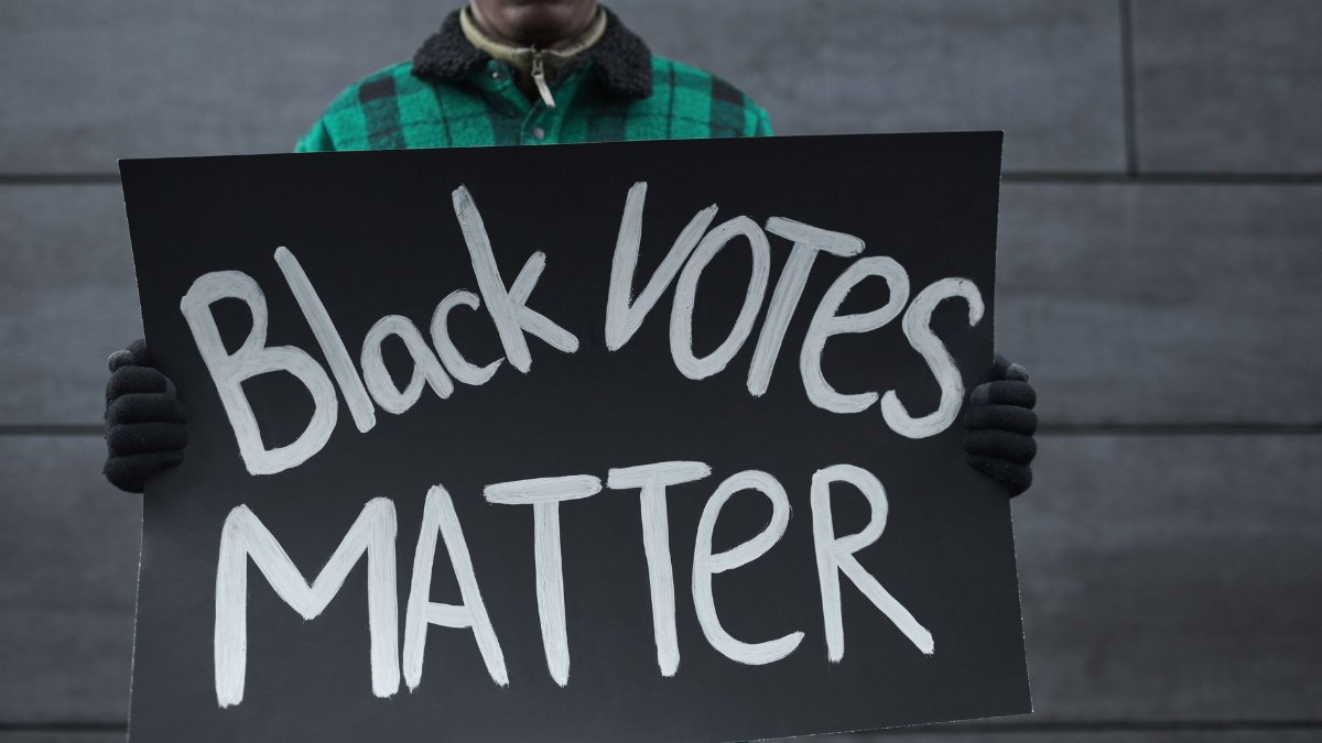 Close-up of a protester holding a Black Votes Matter sign, emphasizing democracy and activism.