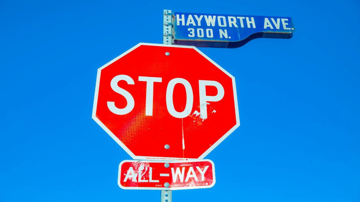 Colorful stop sign at Hayworth Ave intersection against a clear blue sky.