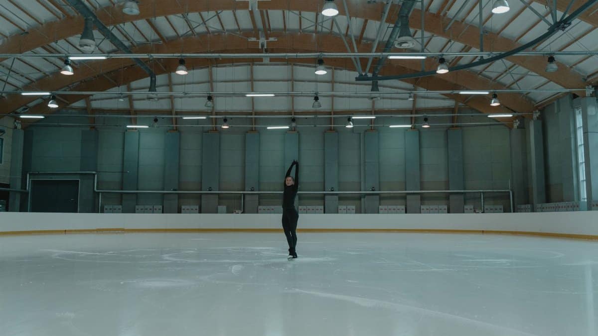 A skilled figure skater rehearses on an indoor rink, showcasing balance and grace.
