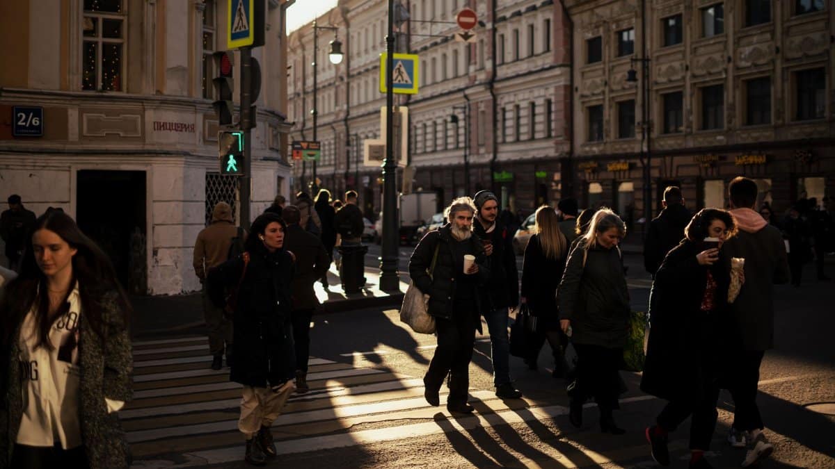 People crossing a city street at a crosswalk during the late afternoon, showcasing urban life.