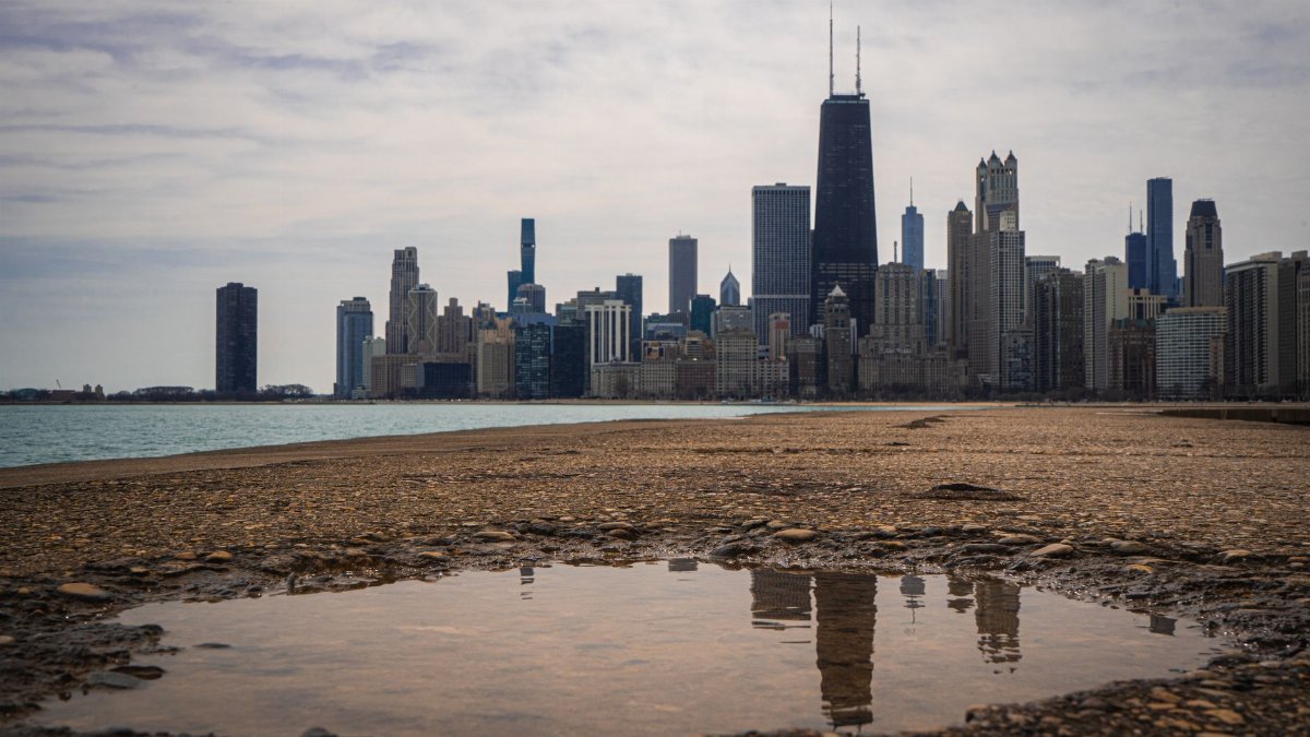 Beautiful view of the Chicago skyline with skyscraper reflections on wet ground under cloudy skies.