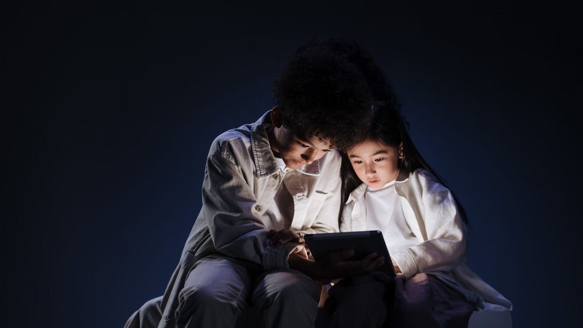 Two children engrossed in a tablet screen, highlighting digital engagement