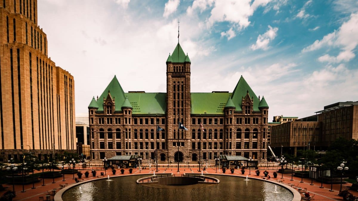 Stunning view of Minneapolis City Hall with its distinctive green roof and a tranquil fountain in the foreground.