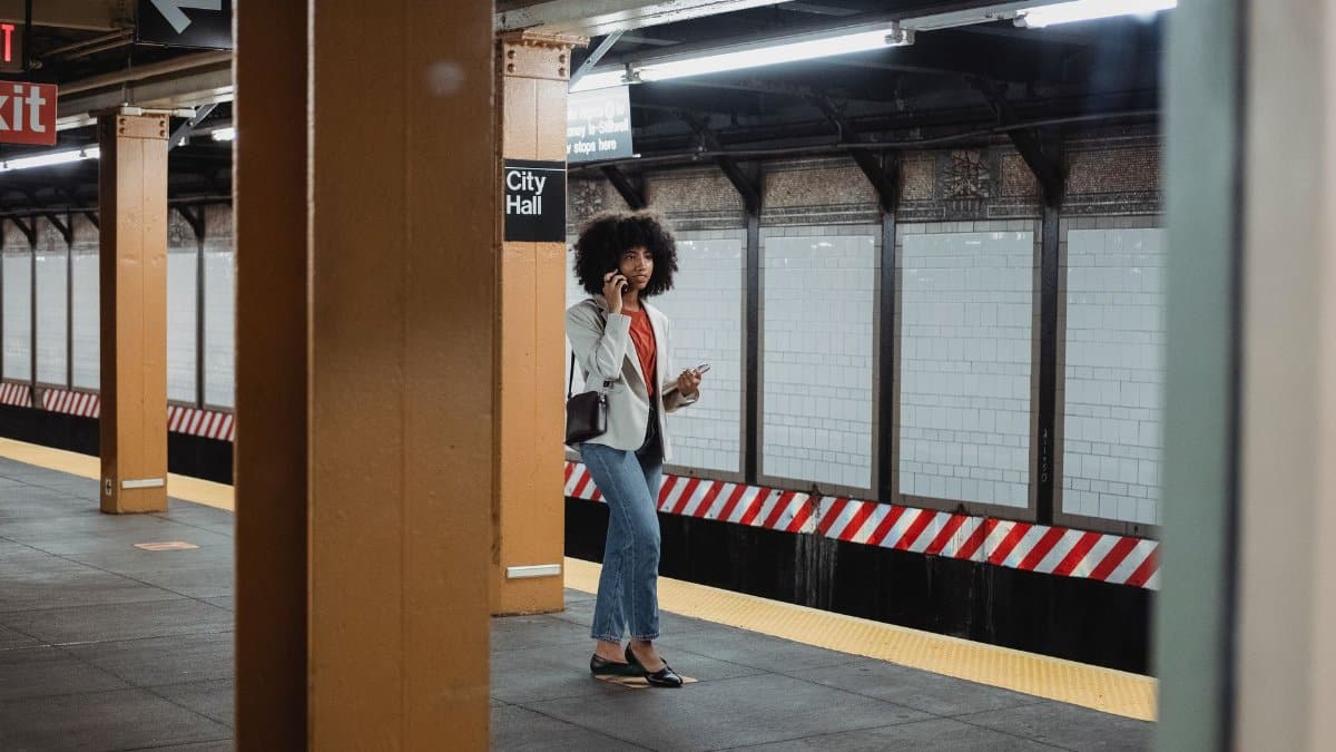 A woman with afro hair making a phone call while waiting at City Hall subway station.