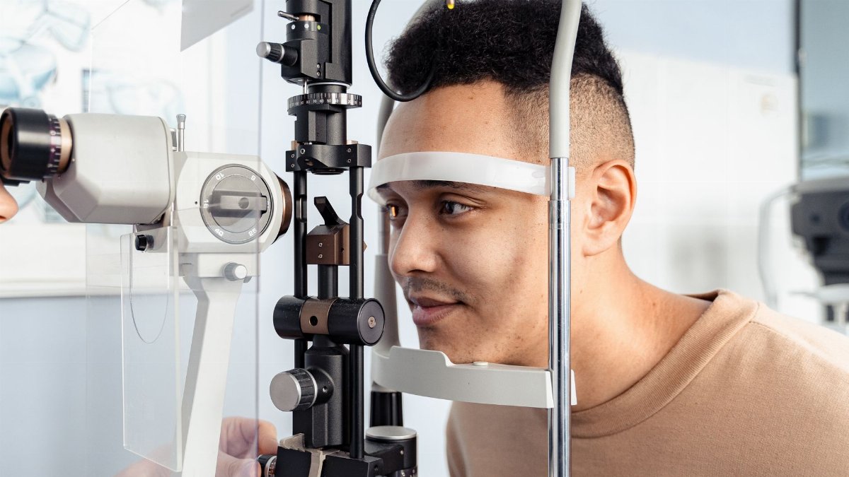 A young man having an eye examination with a slit lamp in a clinic setting.