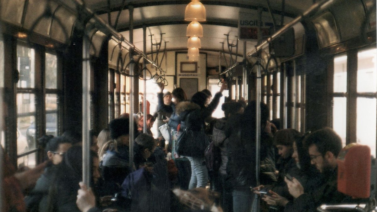 A busy train interior filled with commuters during daytime travel.