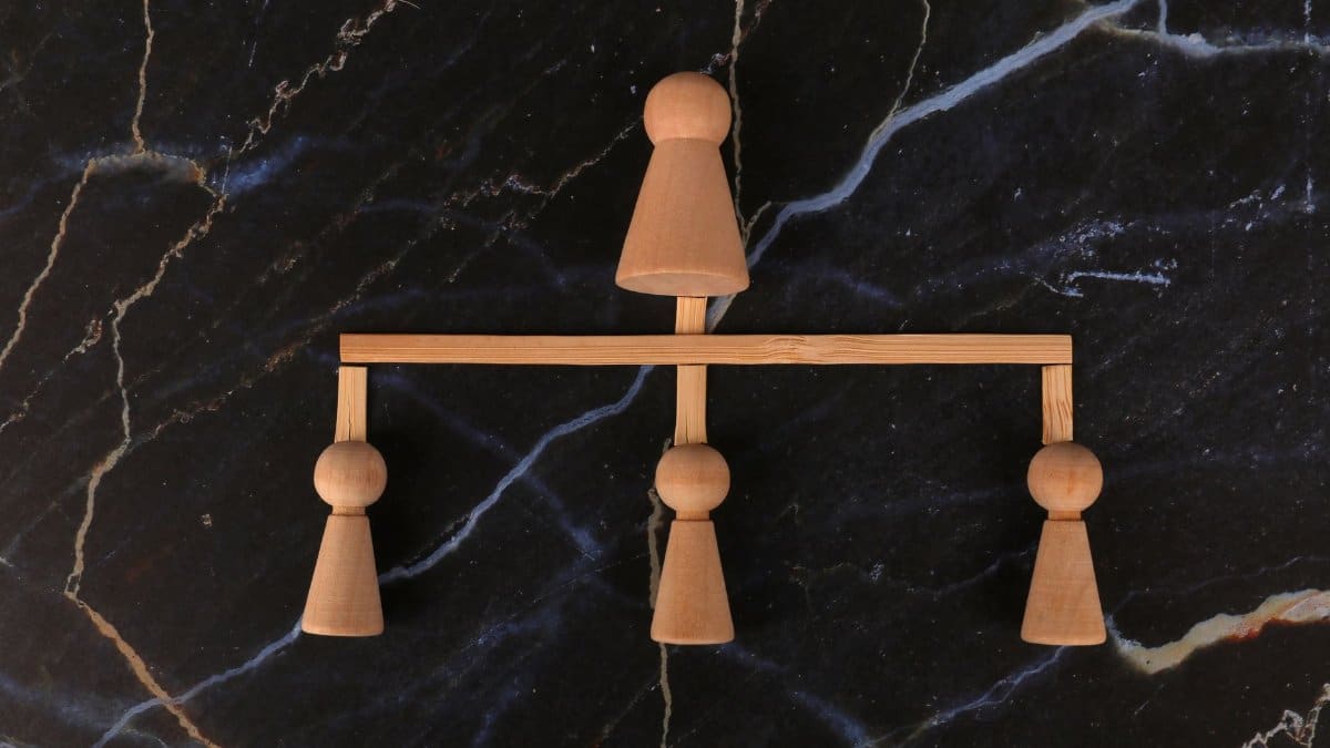 Artistic minimalist wooden balancing scale on dark marble surface, showcasing symmetry.