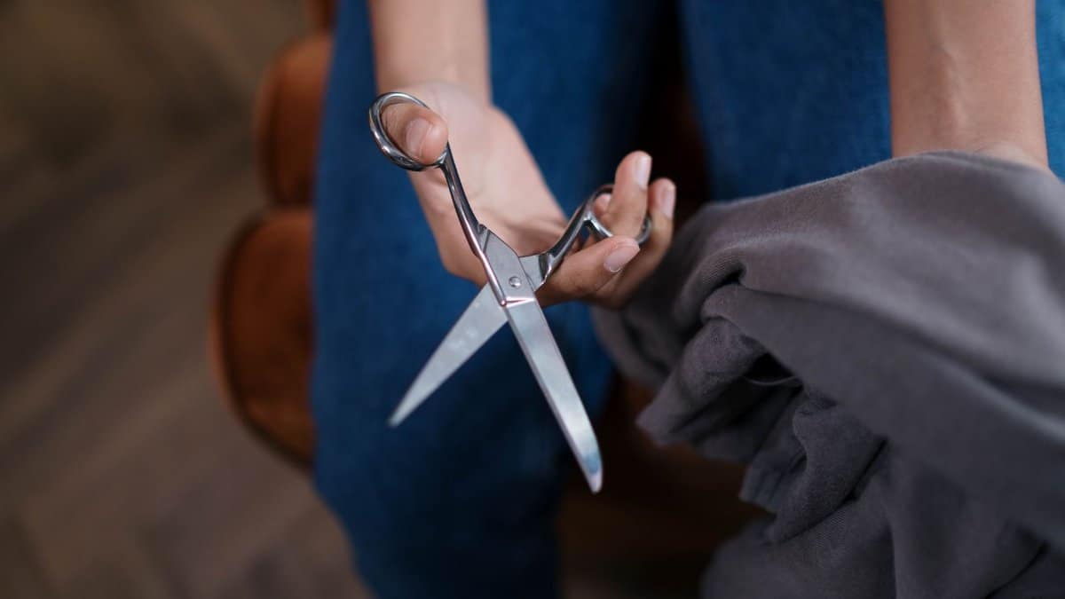 A detailed view of hands cutting fabric with scissors, perfect for tailoring concepts.