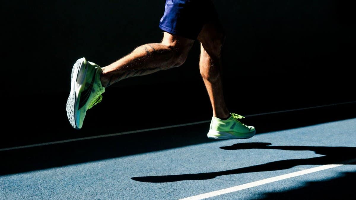 A runner's legs in motion casting a shadow on a track in Bragança Paulista, Brazil.