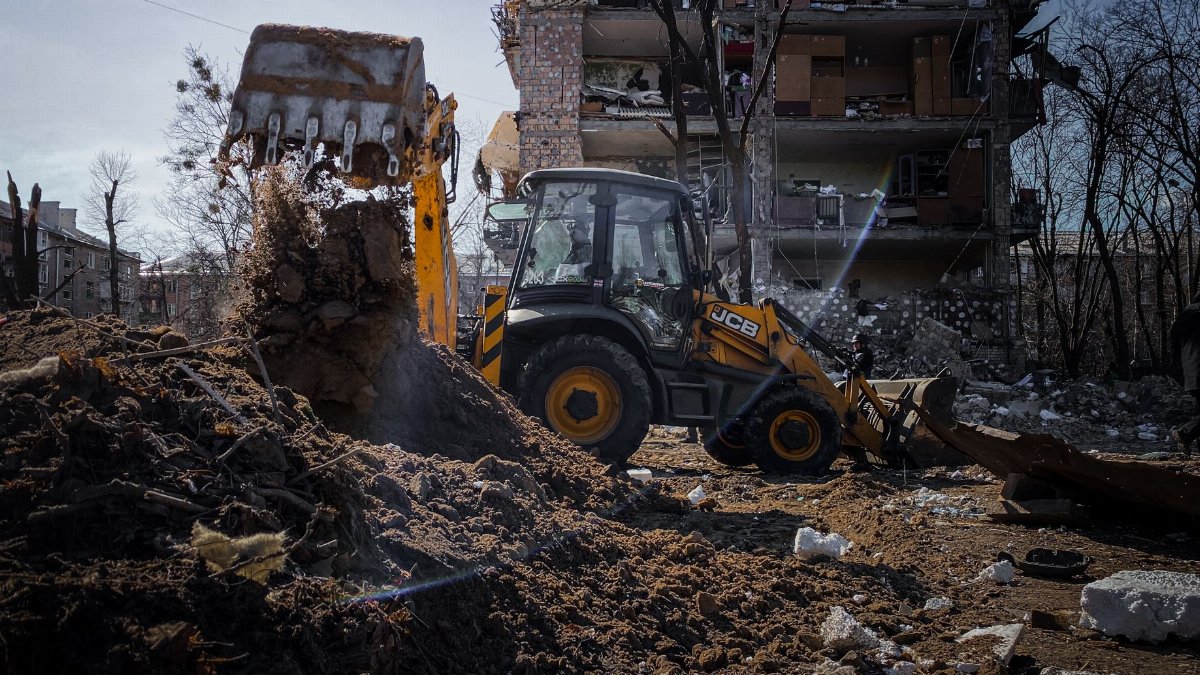 Excavator demolishing a building in Kyiv, Ukraine amidst rubble and debris.