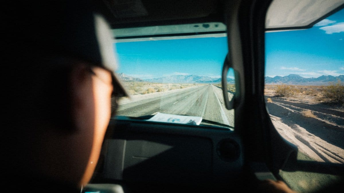 Experience a scenic drive through Mojave Desert with mountains in the background.