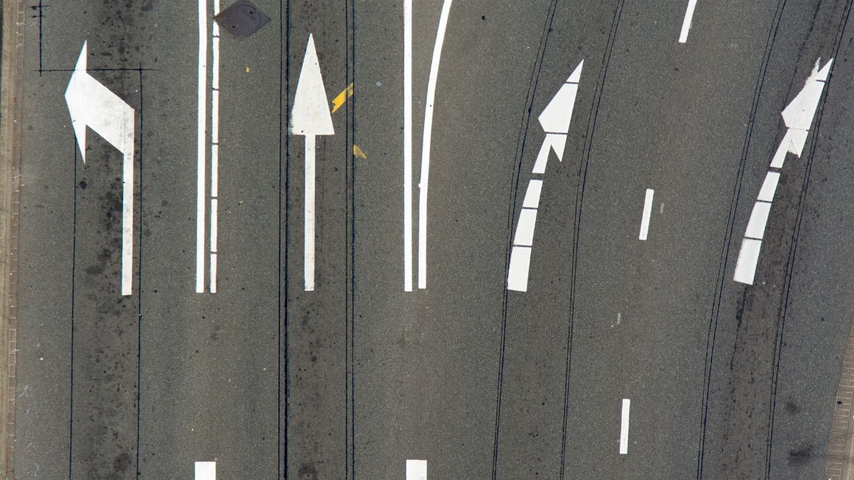 High-angle view of asphalt road with directional arrows and lane markings.