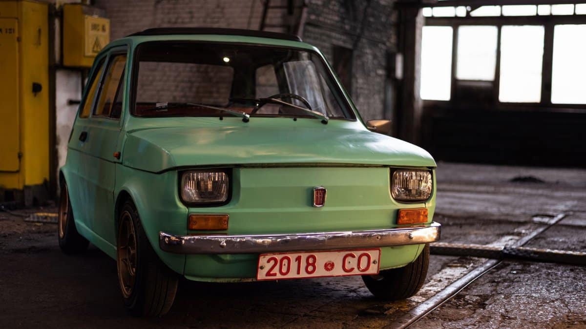 Mint green vintage car parked indoors with industrial background.