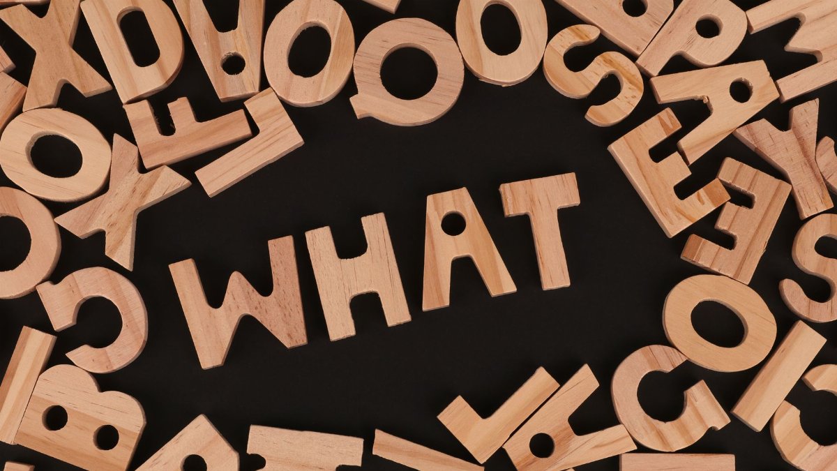 Artistic arrangement of wooden letters spelling 'WHAT' on a black background, offering creative inspiration.