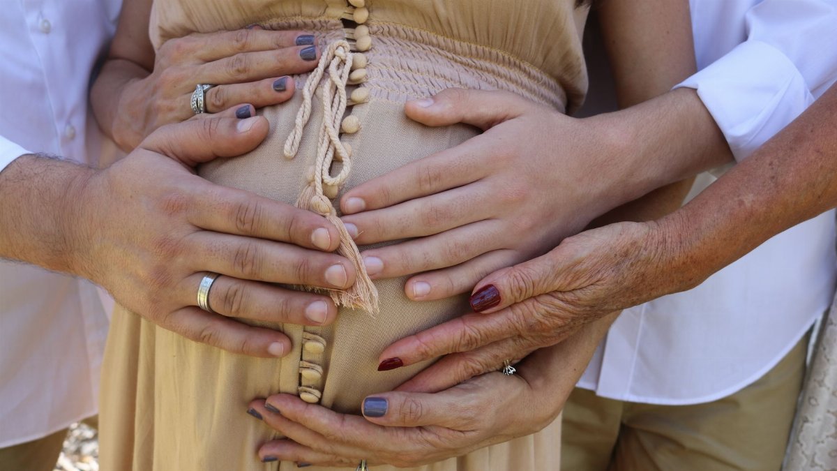 Close-up of family hands touching a pregnant belly, symbolizing love and support during pregnancy.
