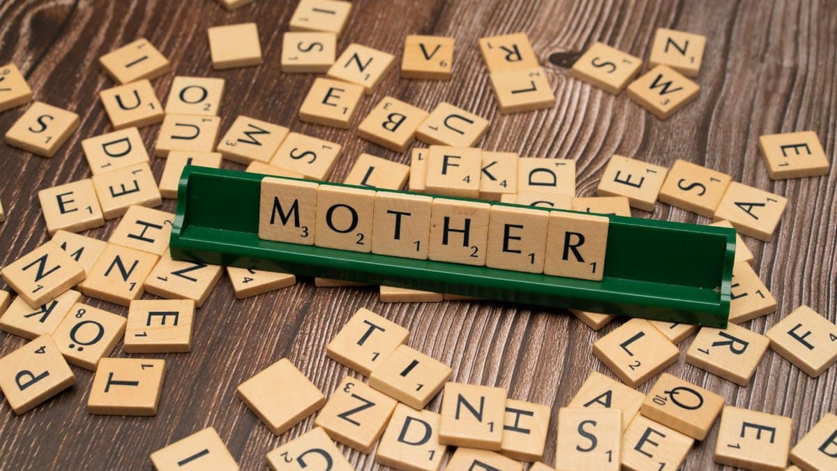 Creative wordplay with wooden letter tiles spelling 'Mother' on a wooden surface.