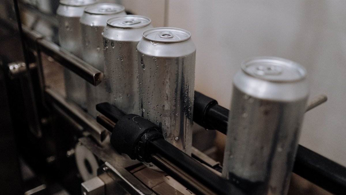 Close-up of aluminum cans with water droplets on a production line, showcasing industrial beverage processing.