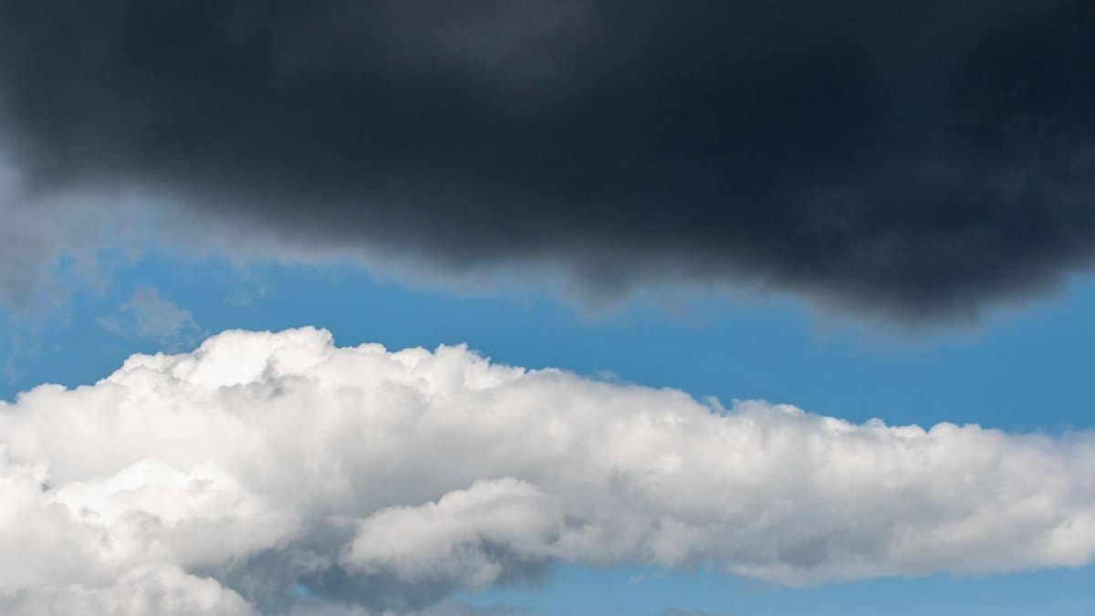 Dark and white clouds contrast against a vibrant blue sky.