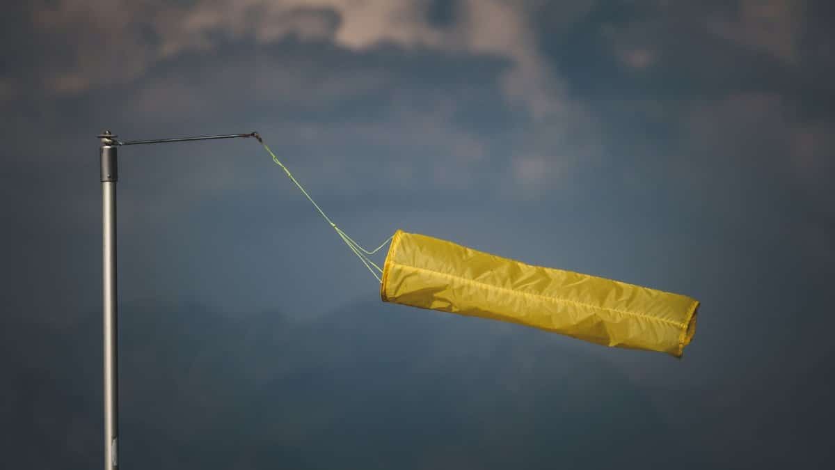 An isolated yellow windsock indicating wind direction against a dark, cloudy backdrop.