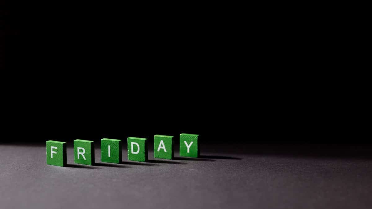 Green letter tiles spelling 'Friday' on a dark background, with dramatic lighting casting shadows.