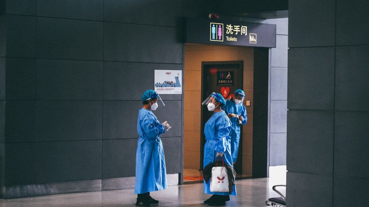 Medical professionals in protective gear near restroom in Shanghai building.