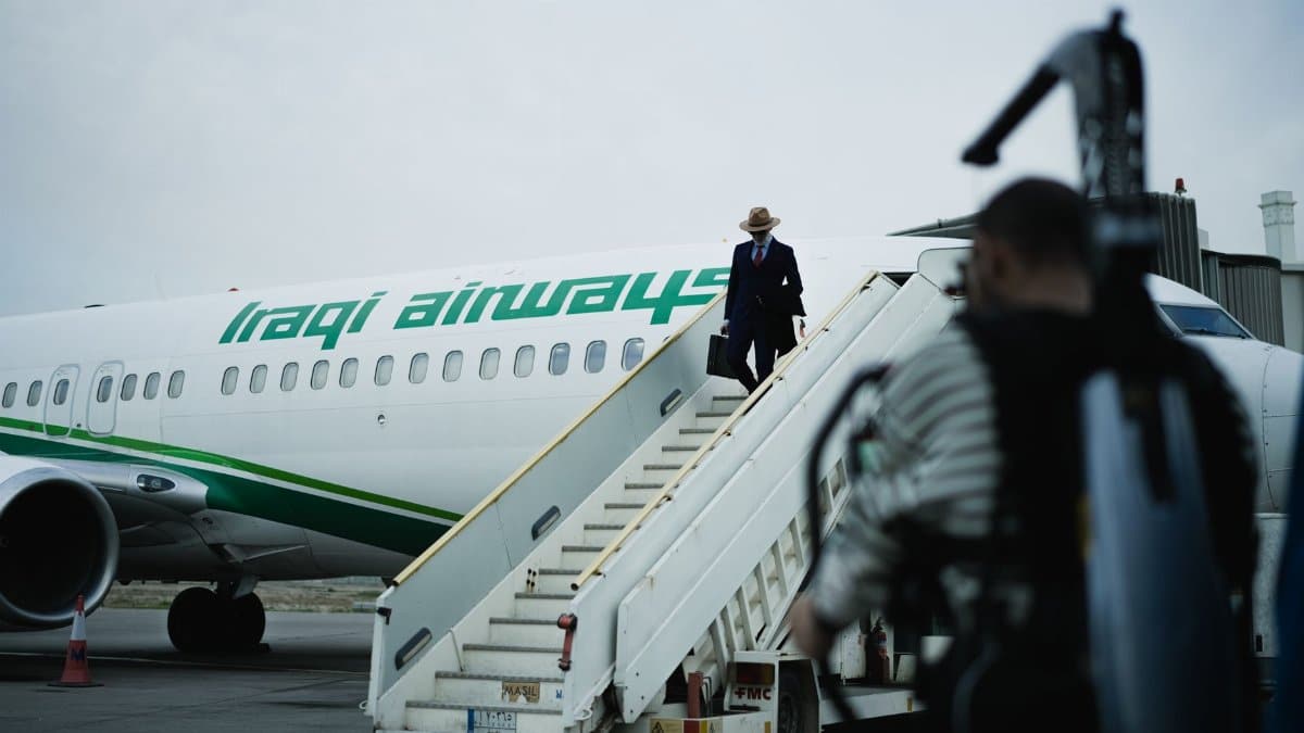 Man boarding Iraqi Airways plane via steps at an airport. Traveler scene