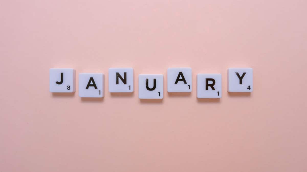 Scrabble-style tiles spell 'January' on a pastel peach background, evoking a fresh start.