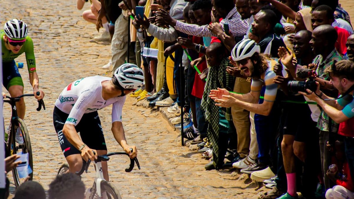 Dynamic road cycling event with enthusiastic crowd on cobblestone street, daytime race action.