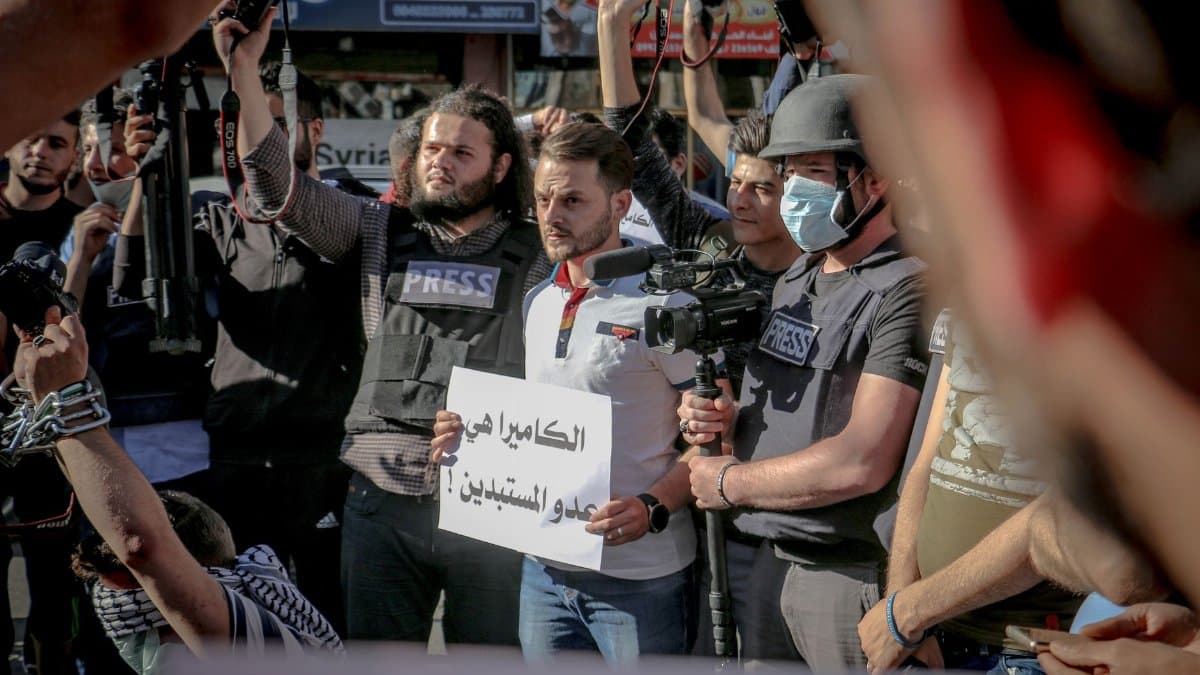Group of ethnic journalists with placard with Arabic inscription and cameras at demonstration against policy