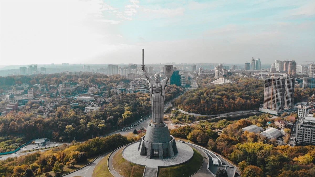 Drone capture of Motherland Monument, featuring Kyiv's cityscape in the background on a clear day